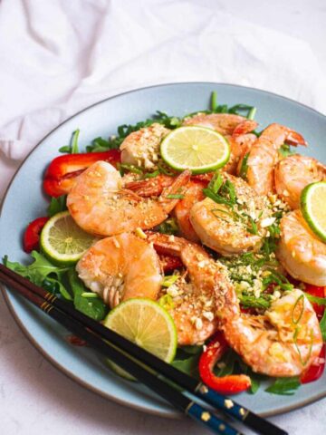 Close up shot of garlic shrimp salad with lime slices.