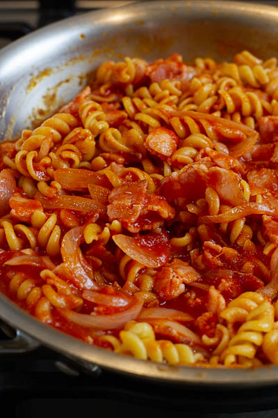 pasta being tossed in tomato sauce.