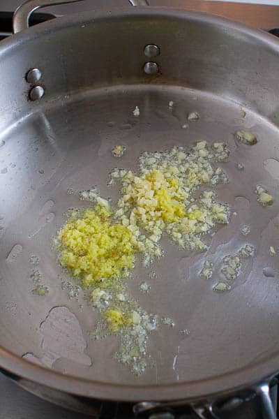 Ginger and garlic being cooking in a pan.