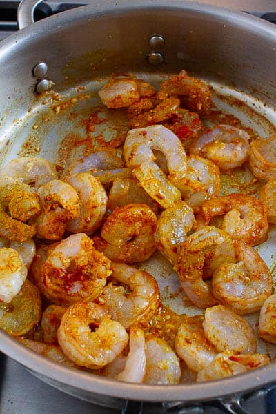 Shrimps being cooked with spices in a pan.