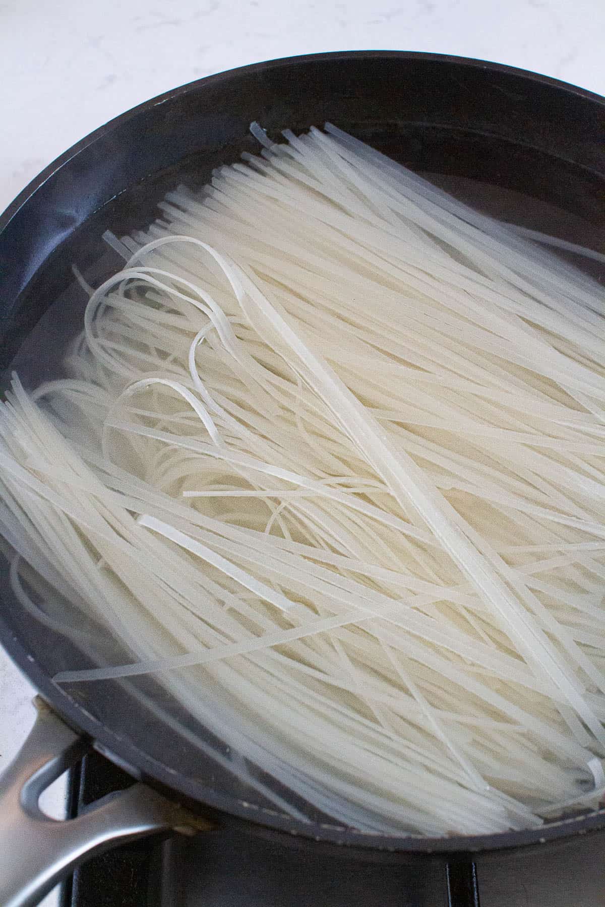Rice noodles being boiled in hot water.