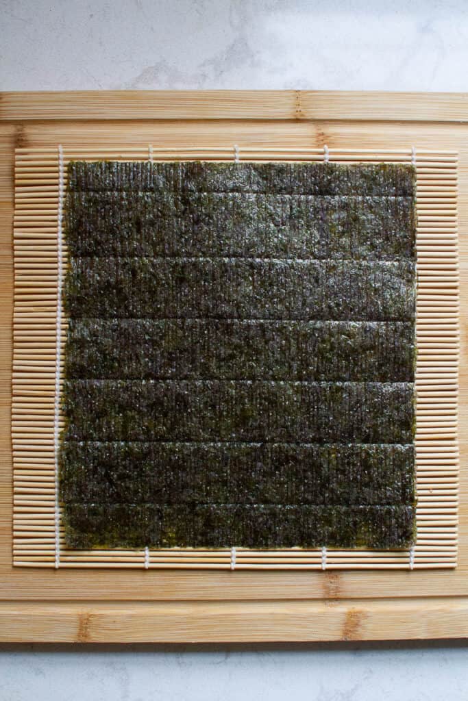 A piece of nori seaweed on a bamboo mat.