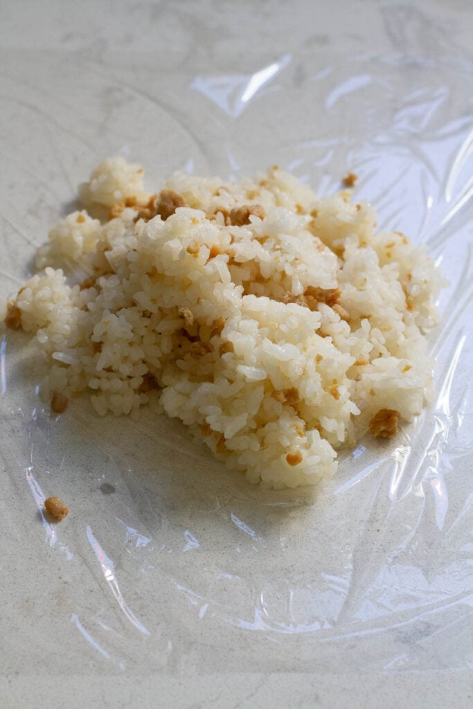 One portion of chicken rice placed on a piece of cling wrap.