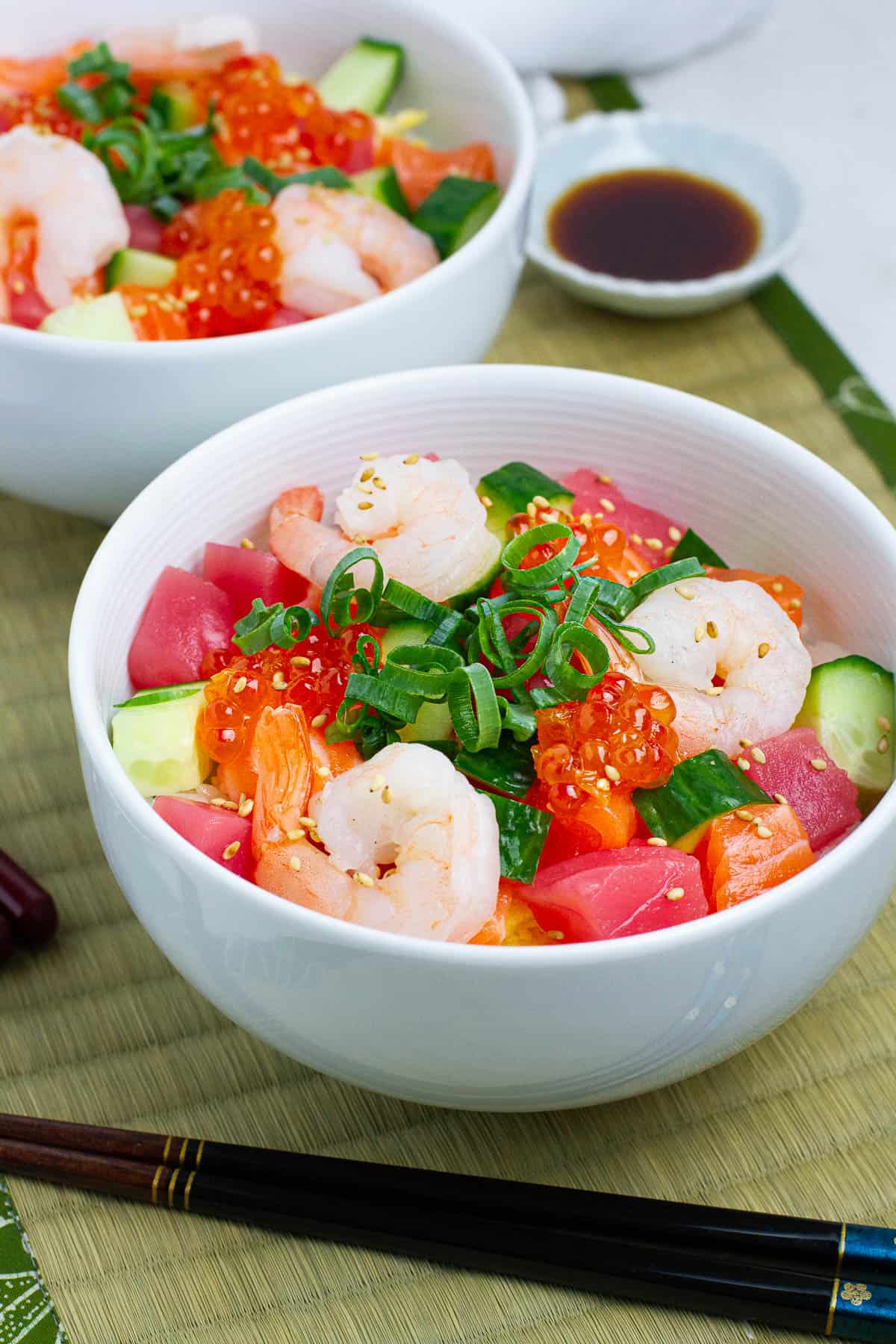 Two bowls of Japanese chirashi bowl with seafood and vegetable toppings. 