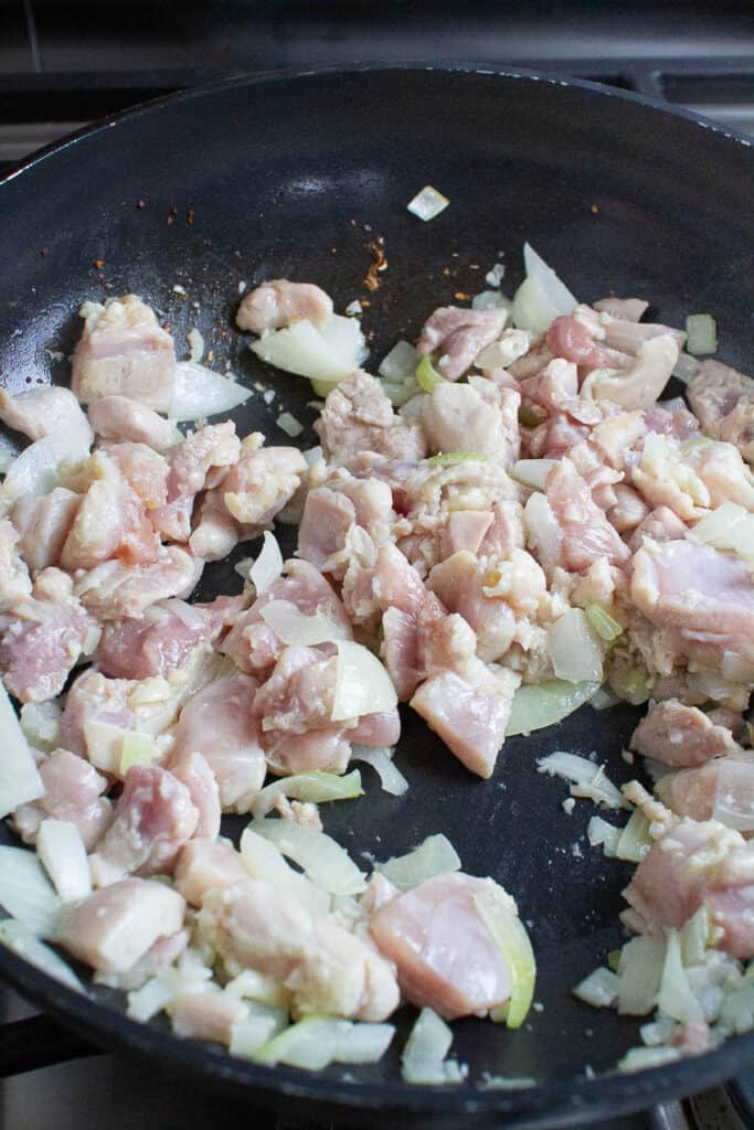 Onion, garlic and chicken being cooked in a pan.