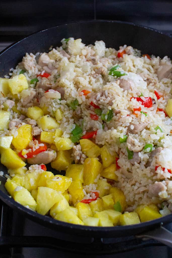 Fried rice and pineapple chunks being cooked in a pan.