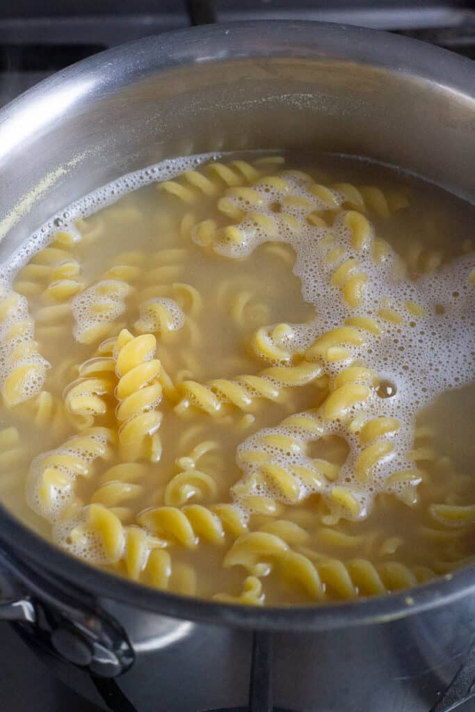 Gluten free rotini pasta being cooked in a saucepan.