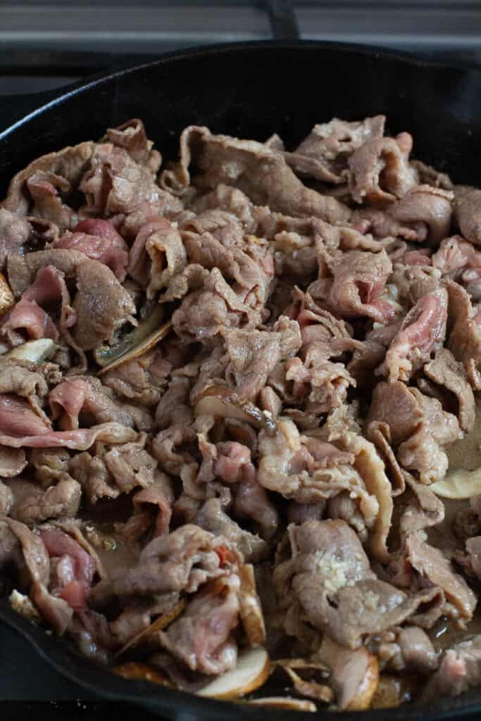 Thinly sliced beef for beef pepper rice being cooked in a skillet.