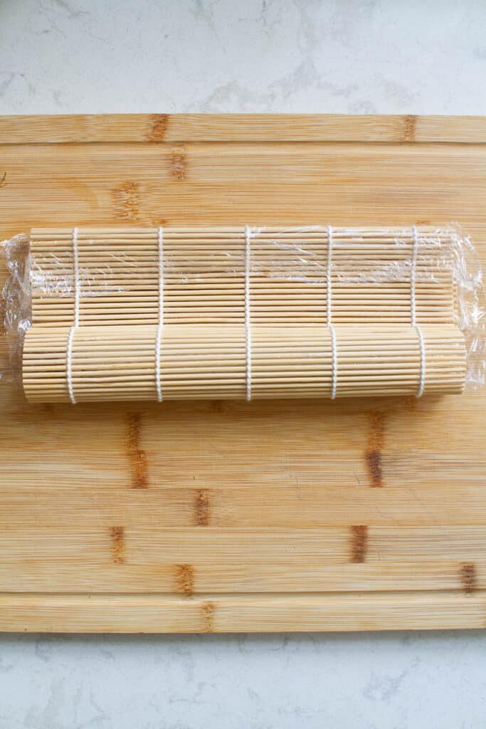 uramaki sushi rolls being wrapped by a bamboo makisu mat.