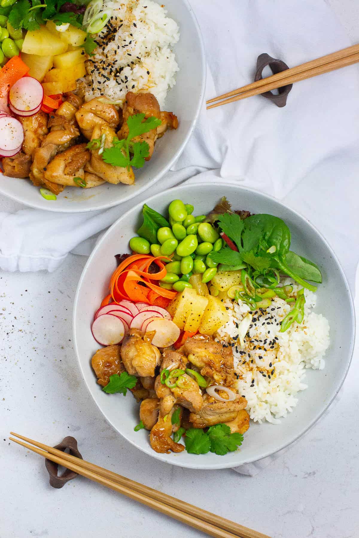 Top view of a bowl of chicken with radishes, carrots and edamame seasonings.