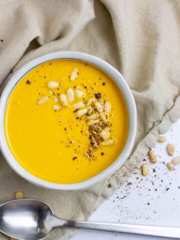 Top view of carrot cumin soup with pine nuts topping.