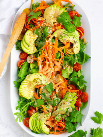Top view of spinach arugula salad with avocado topping.