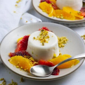 Coconut milk panna cotta with orange slices and pistachio.