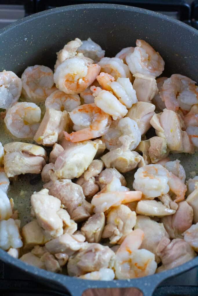 Chicken and shrimp cooked in a skillet.