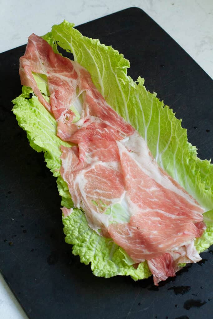 Napa cabbage and pork being layered.
