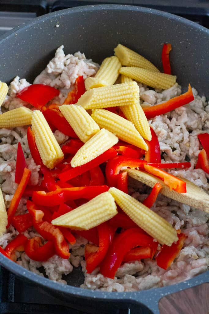 Ground chicken, bell pepper, and baby corn in a pan.