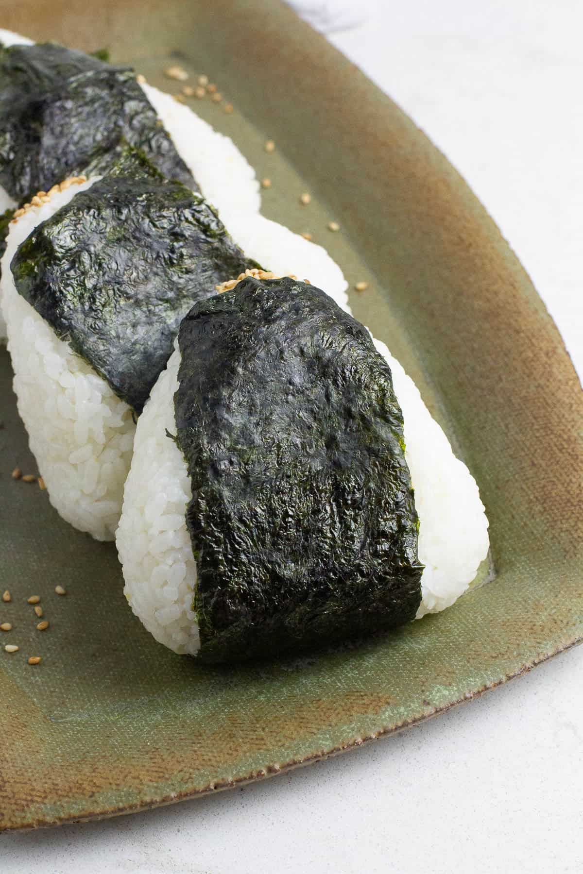 Tuna mayo onigiri rice balls on a rectangular plate.