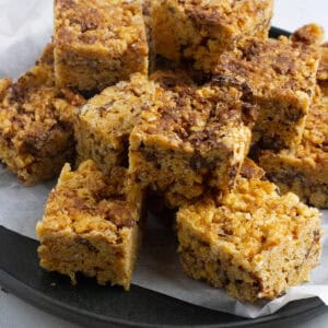 Chocolate peanut butter rice krispie treats piled up on a plate.