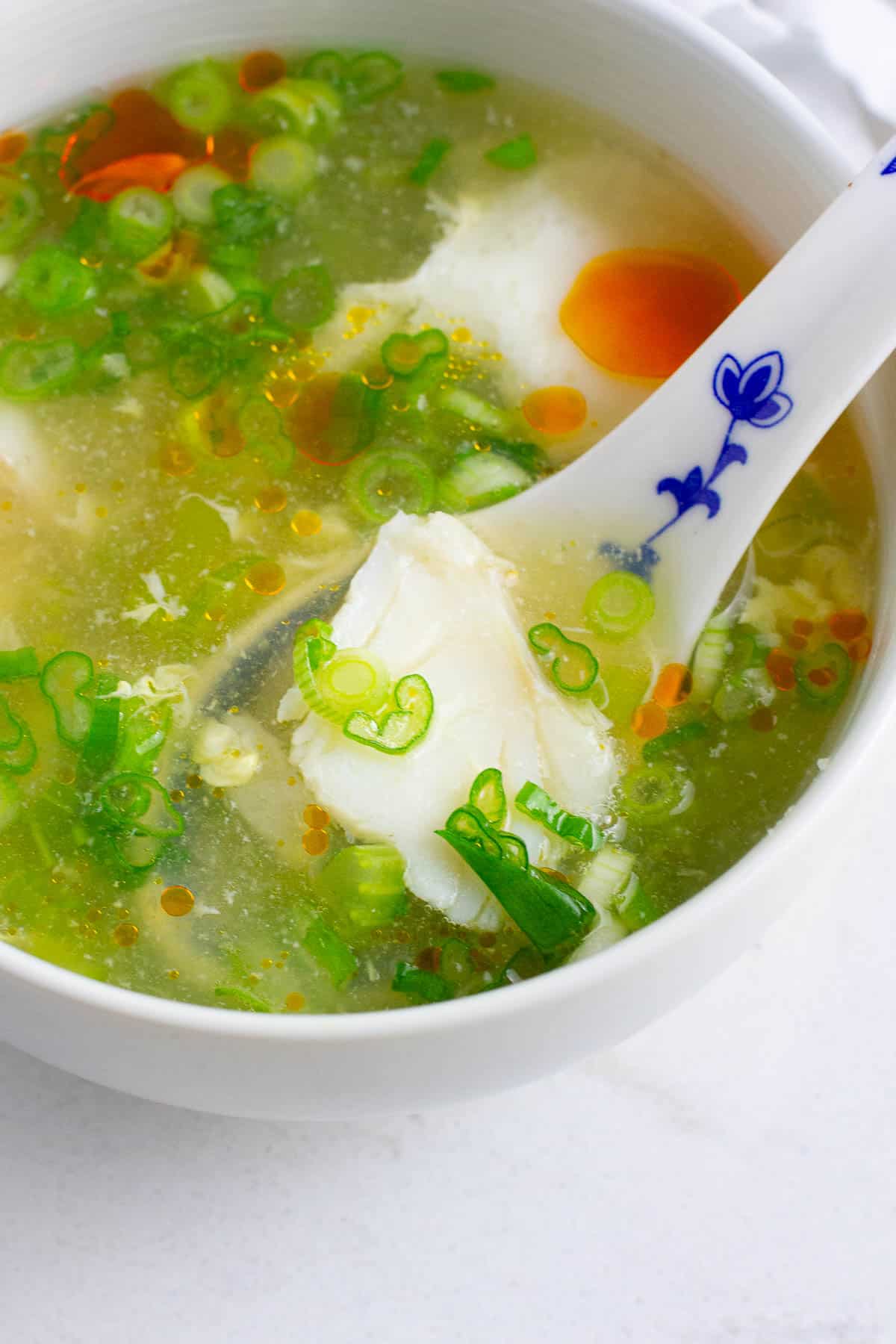 A chunk of cod in a soup spoon.