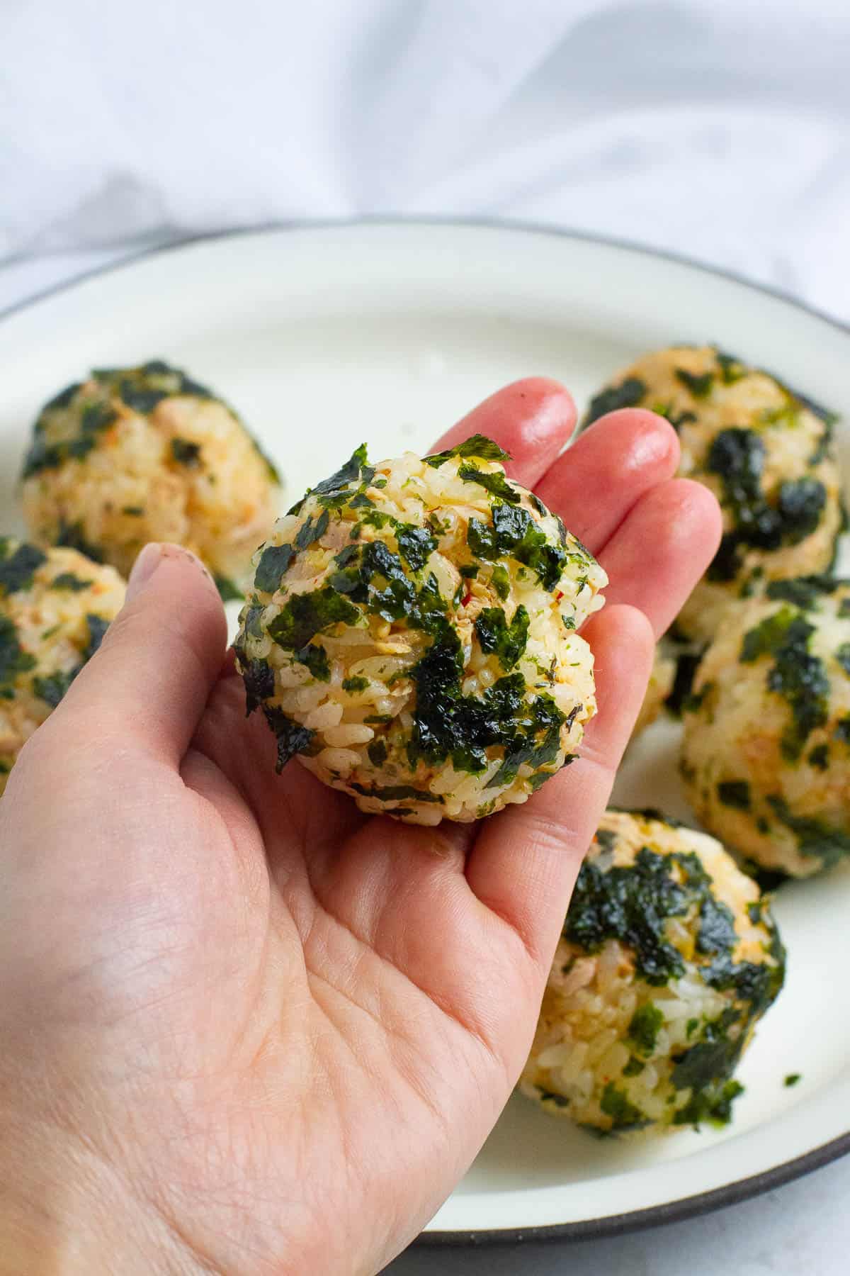 A Korean seaweed rice ball held in hand.