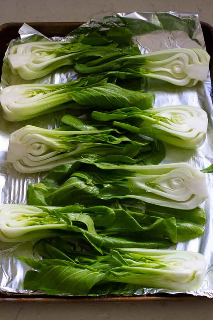Halved baby bok choy on a baking sheet.