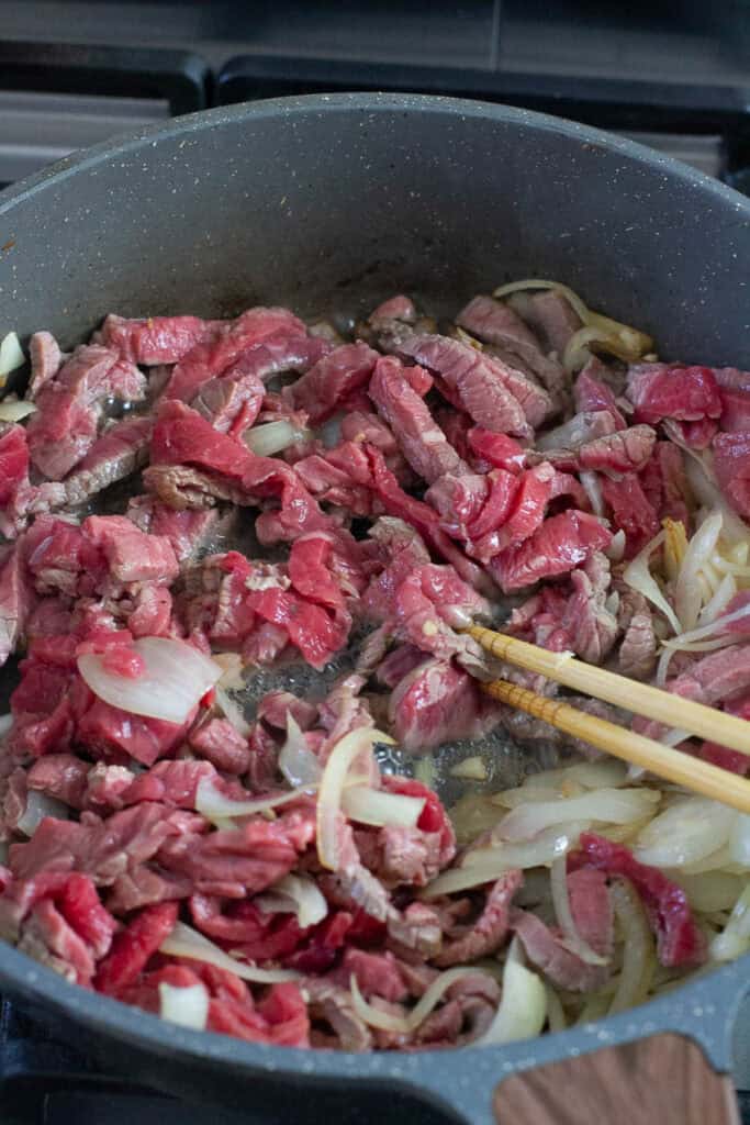 Beef and onion cooked in a skillet.