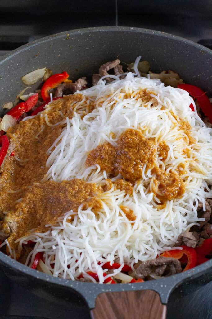 Beef satay noodles tossed in a skillet.