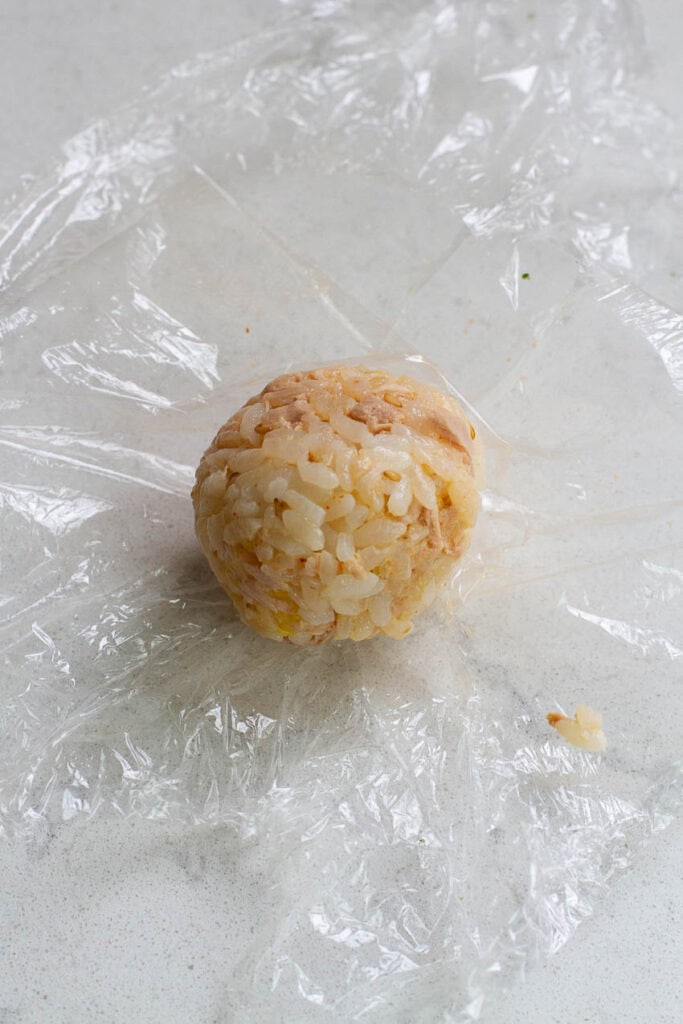 A rice ball on a cling wrap.