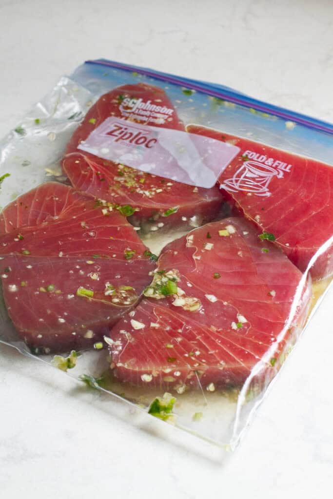 Marinated tuna steaks in an airtight bag.