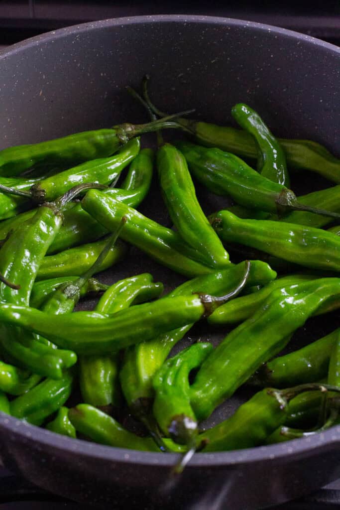 Shishito peppers in a frying pan.