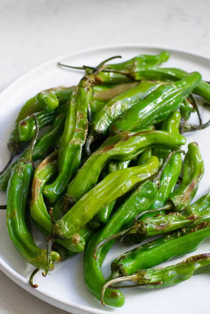 Cooked shishito peppers on a plate.