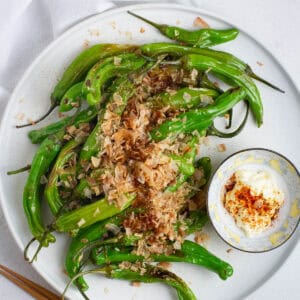Top view of shishito peppers on a round plate.