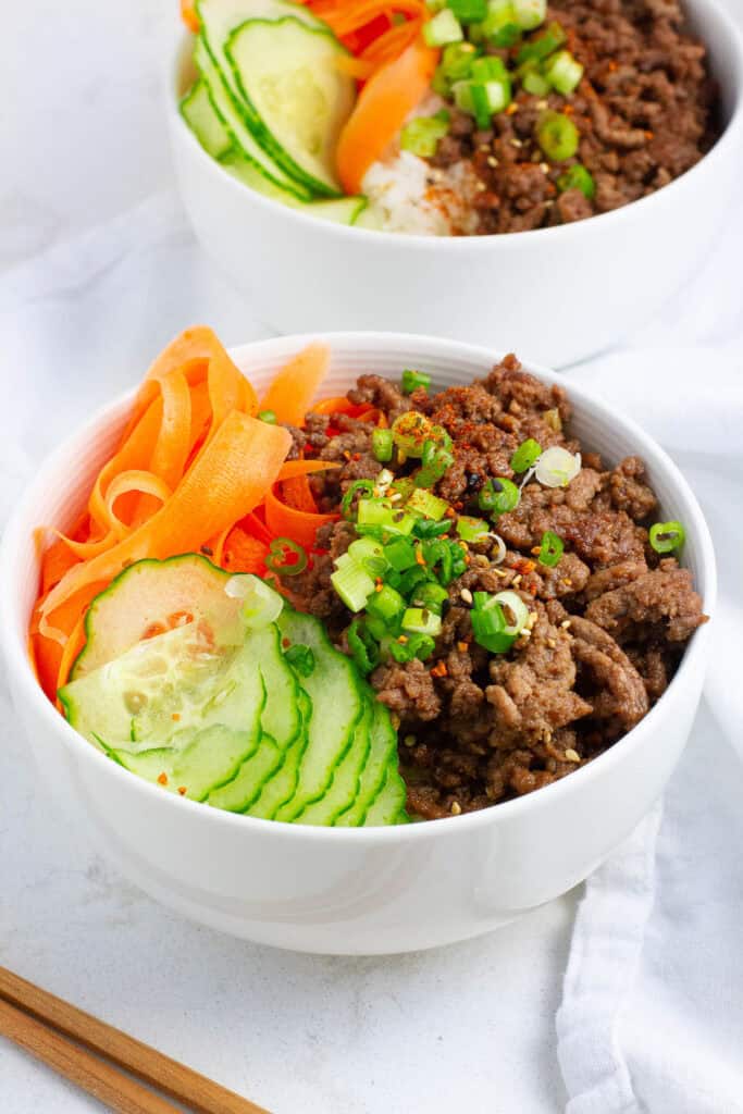 Two bowls of beef teriyaki bowls with vegetables.