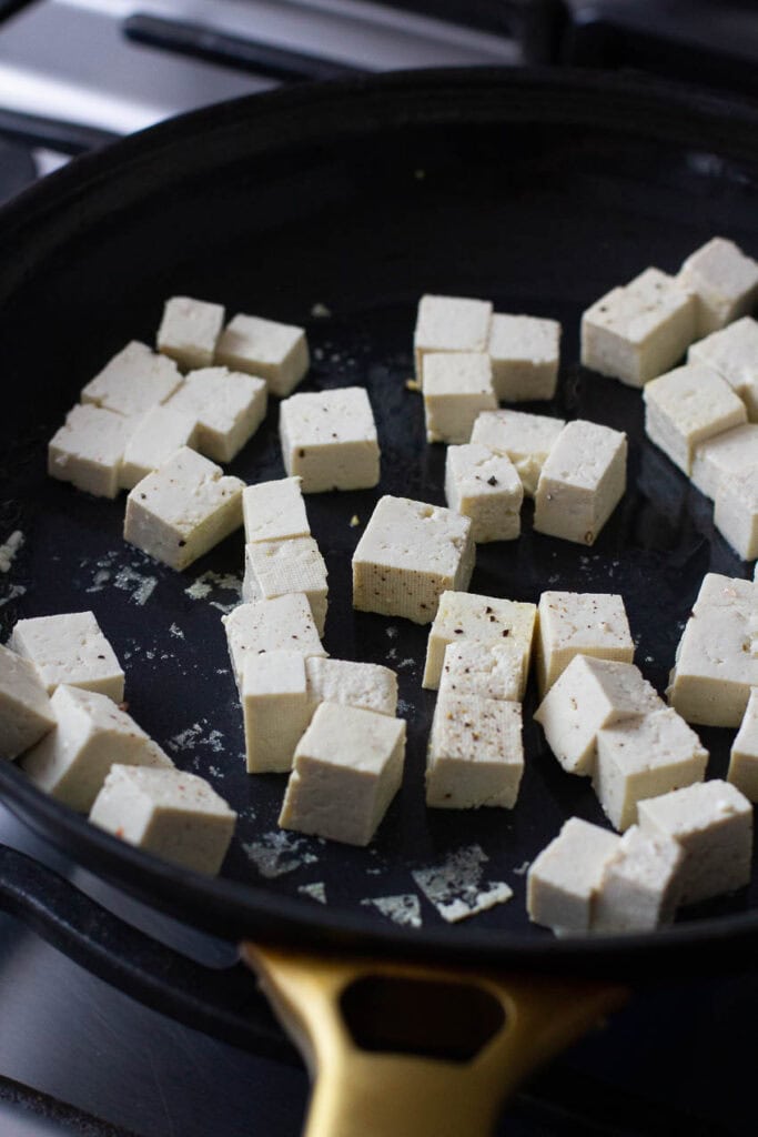Tofu being cooked in a pan.