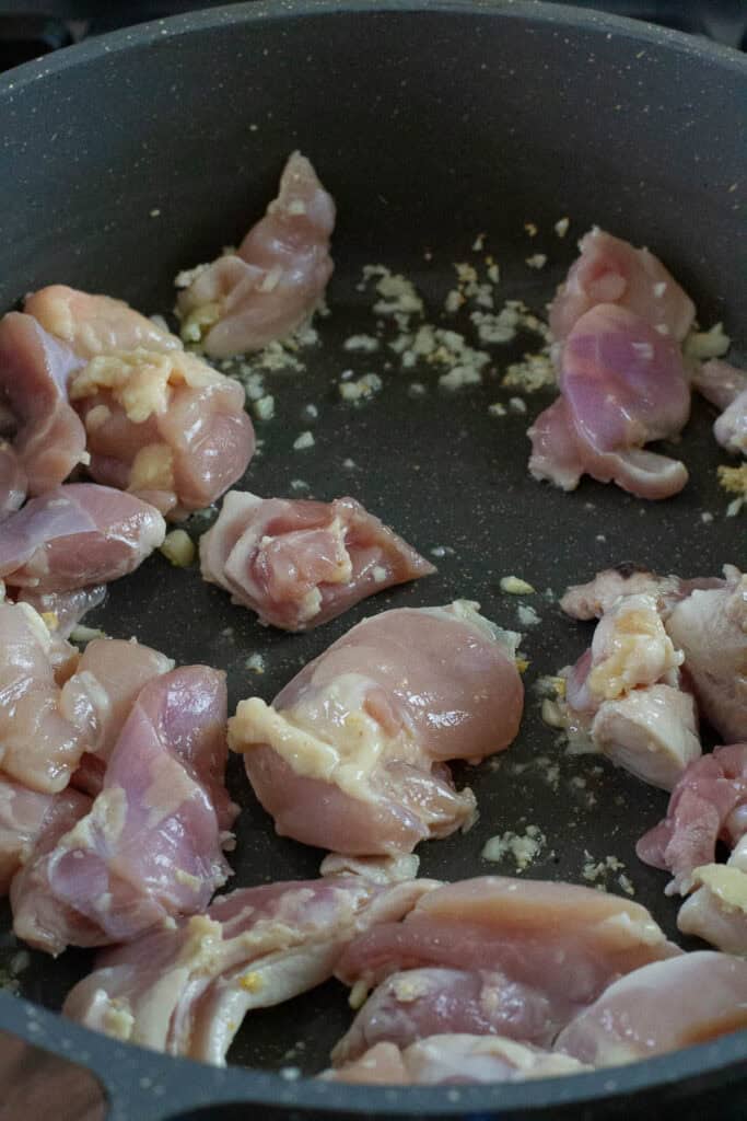 Chicken thighs and garlic cooked in a pan.