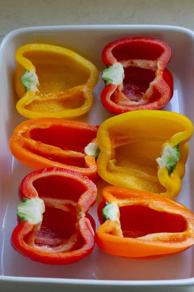 Halved bell peppers in a baking dish.