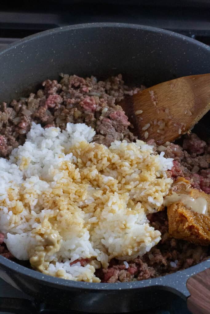 Rice and beef being cooked in a pan.